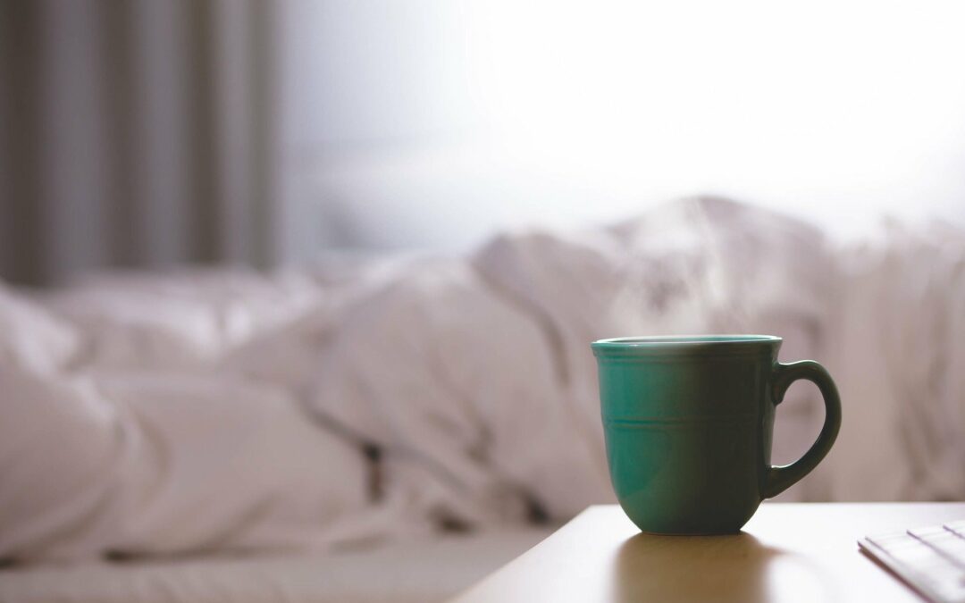 cup of coffee in front of a messy bed